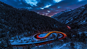 Long Exposure Light Trails on a Snowy Mountain Road at Dusk HD wallpaper