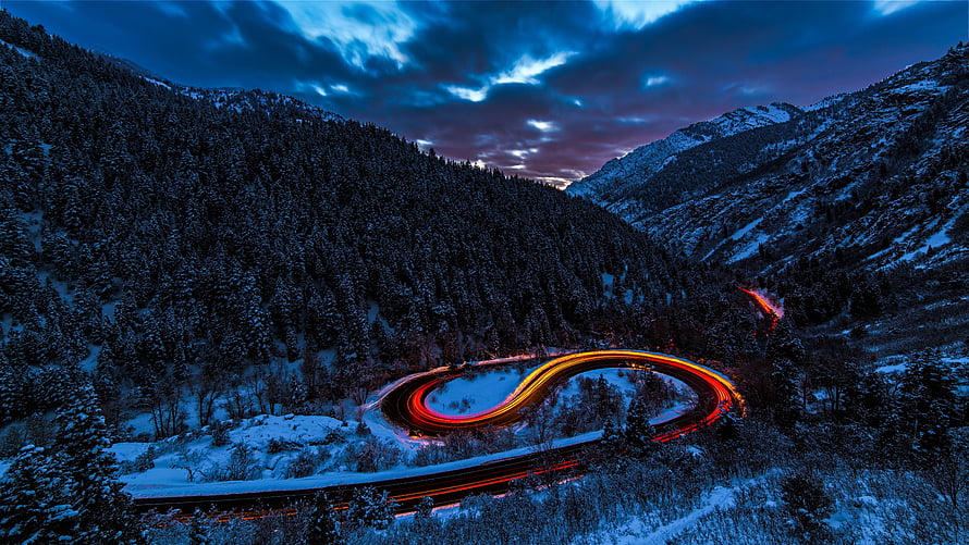 Long Exposure Light Trails on a Snowy Mountain Road at Dusk HD wallpaper