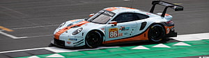 Porsche 911 GT3 R race car in white and orange livery on a motorsport circuit HD wallpaper