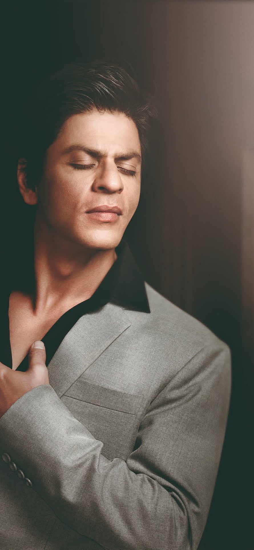 Shah Rukh Khan in a grey suit with eyes closed in a moody studio portrait HD phone wallpaper