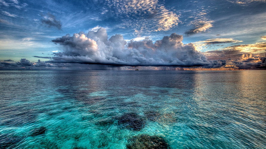 Dramatic Storm Clouds Over Turquoise Ocean Waters at Sunset HD wallpaper