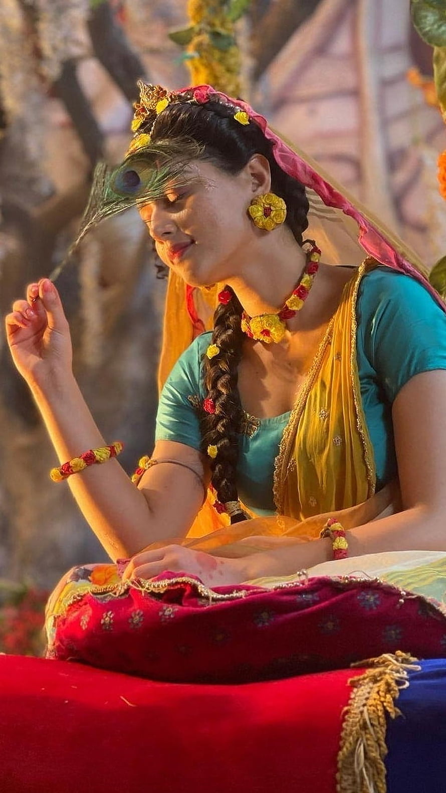 Woman in traditional Indian attire holding a peacock feather with floral jewelry and vibrant colors, Mallika Singh 12, actress, beautiful, Mallika Singh HD phone wallpaper