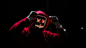 Mysterious figure in a red hoodie wearing a glowing LED mask with X eyes in the dark HD wallpaper