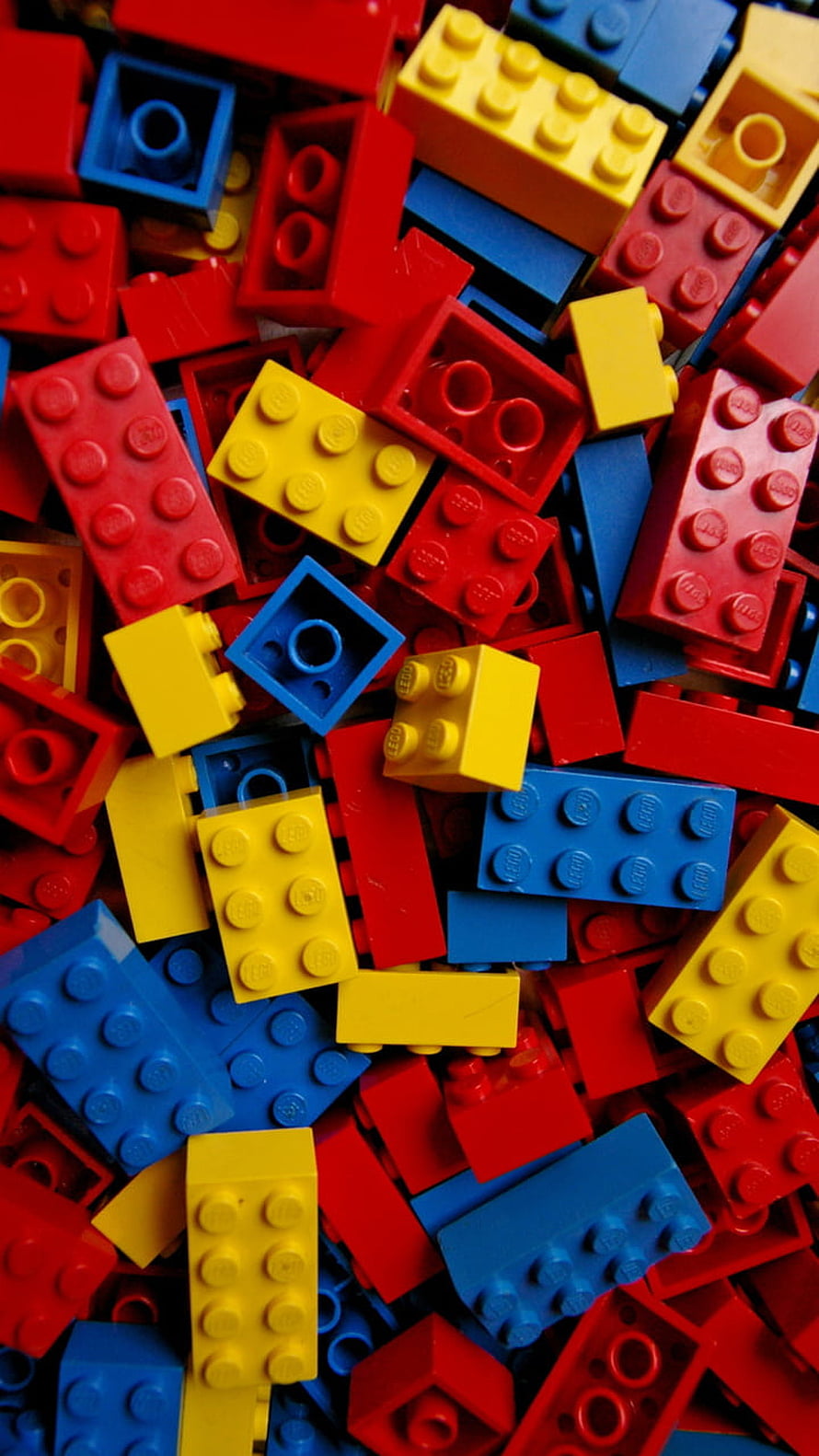 Vibrant pile of red, blue, and yellow LEGO bricks scattered in a colorful close-up HD phone wallpaper