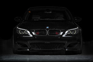 Front View of a Sleek Black BMW M5 with Angel Eyes and Aggressive Grille HD wallpaper