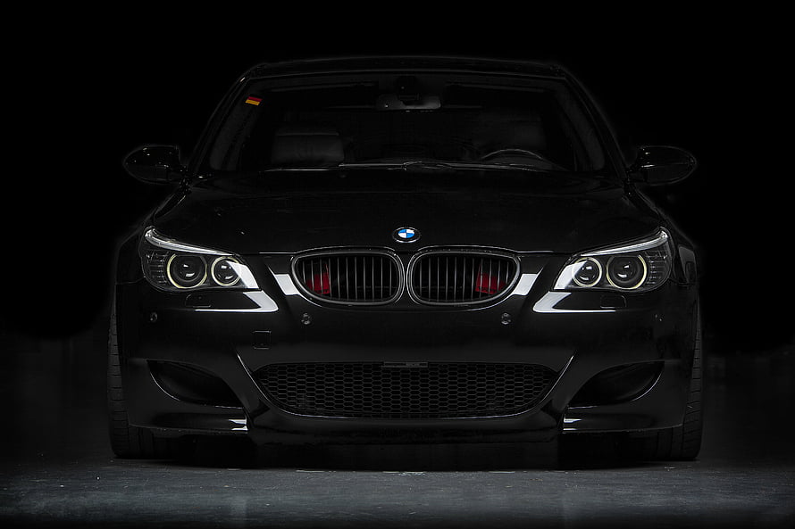 Front View of a Sleek Black BMW M5 with Angel Eyes and Aggressive Grille HD wallpaper