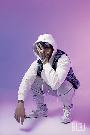 Central Cee Crouching in White Hoodie and Camo Vest on Purple Background HD phone wallpaper
