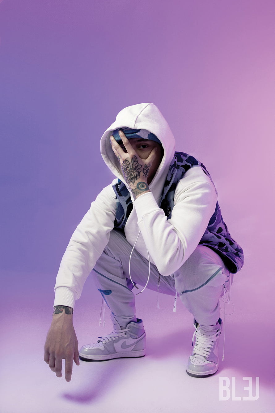 Central Cee Crouching in White Hoodie and Camo Vest on Purple Background HD phone wallpaper