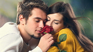 Romantic couple sharing a red rose in a tender outdoor embrace HD wallpaper