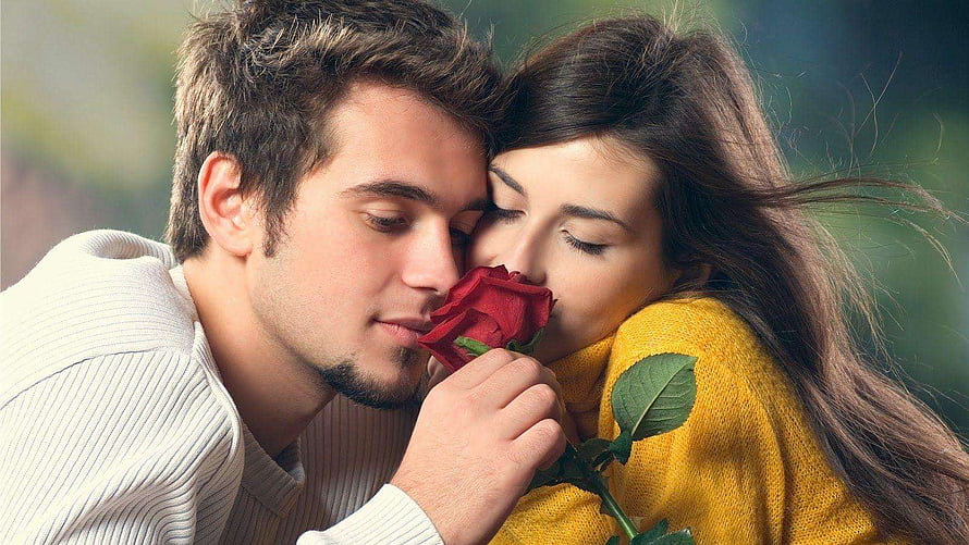 Romantic couple sharing a red rose in a tender outdoor embrace HD wallpaper