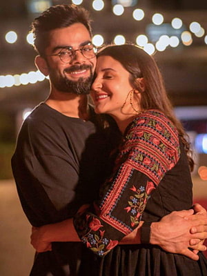 Virat Kohli and Anushka Sharma Embracing Under Warm String Lights at Night HD phone wallpaper