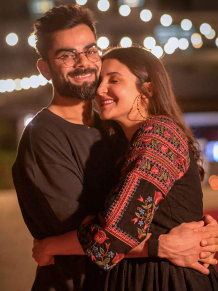 Virat Kohli and Anushka Sharma Embracing Under Warm String Lights at Night HD phone wallpaper