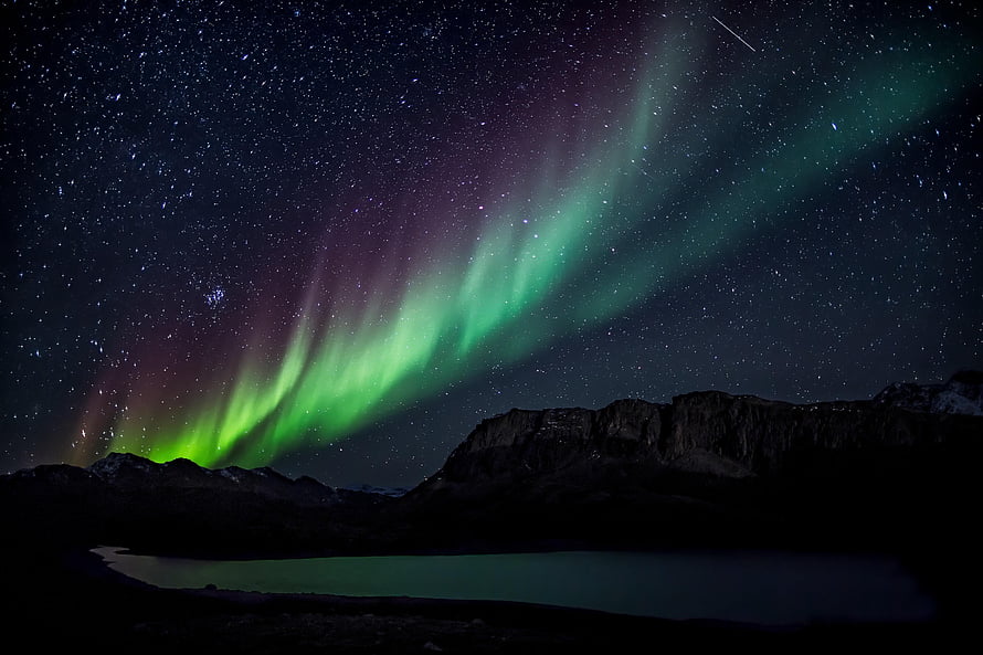 Vibrant Aurora Borealis Dancing Over Rugged Mountains and a Serene Night Lake HD wallpaper
