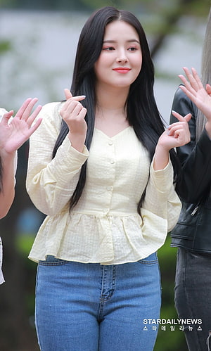 Nancy from Momoland Waving With Finger Hearts In Yellow Top And Blue Jeans HD phone wallpaper