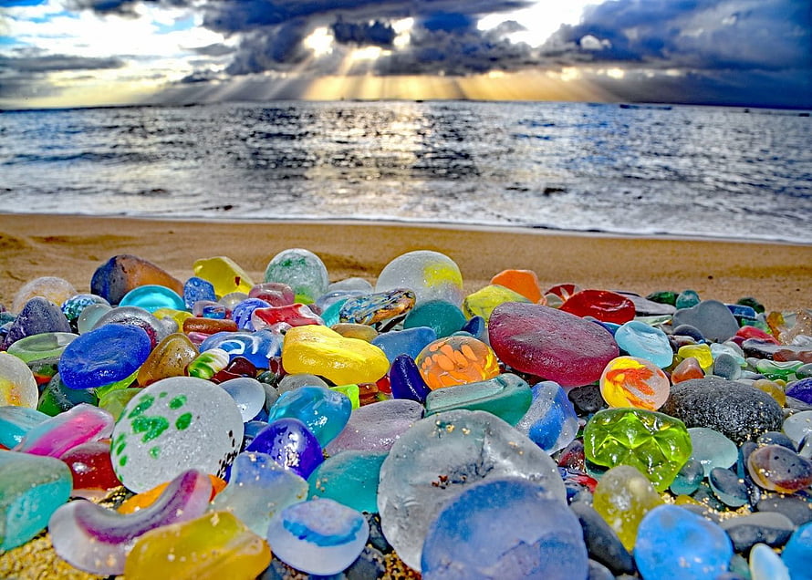 Colorful Sea Glass Stones on Sandy Beach with Ocean Sunset Background HD wallpaper