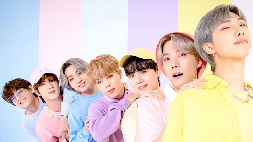 BTS members posing together in colorful pastel outfits against a striped background HD wallpaper