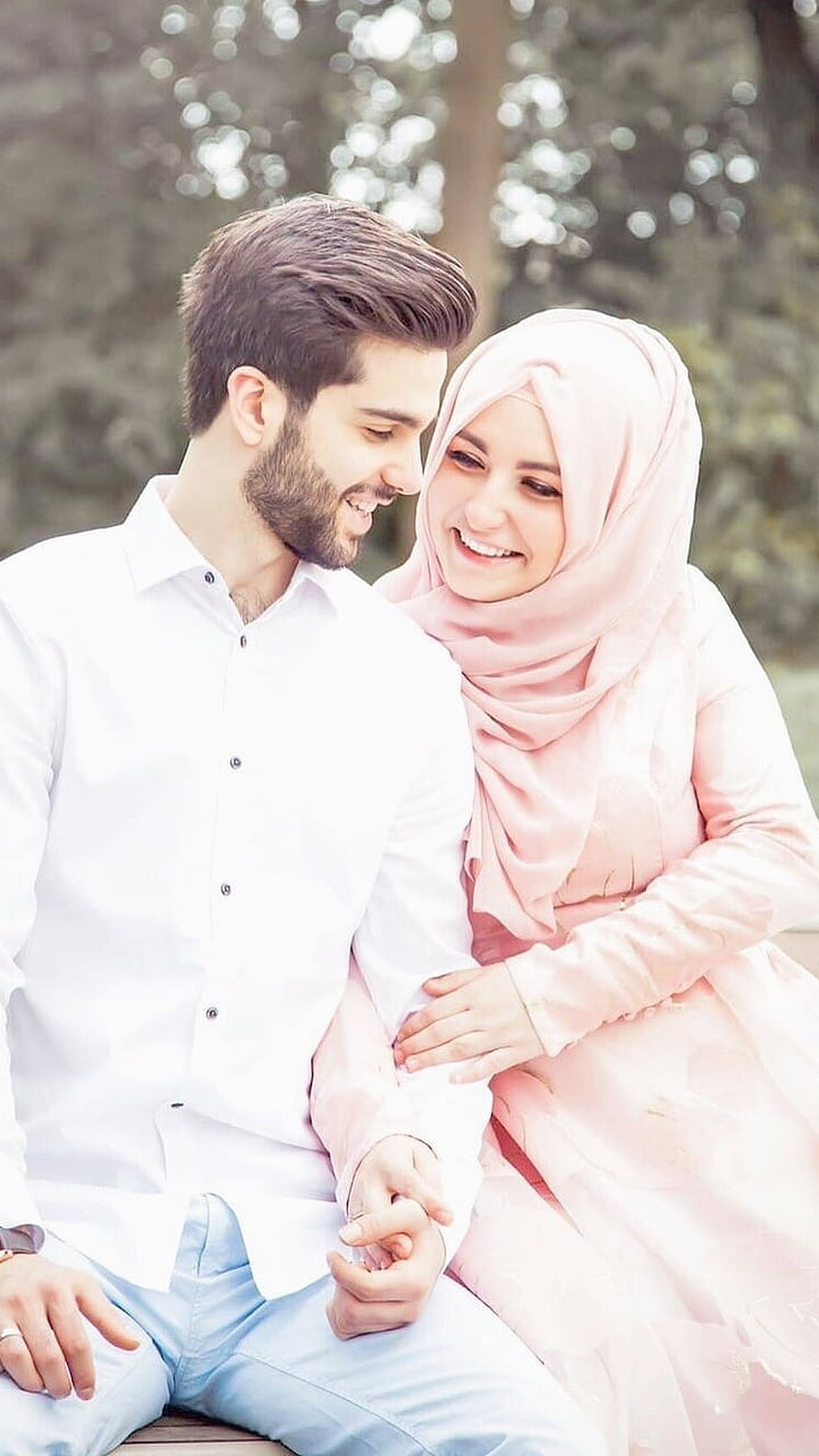 Smiling Muslim couple in soft pink hijab and white shirt sharing a tender moment outdoors HD phone wallpaper