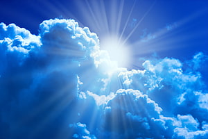 Bright Sun Rays Shining Through Fluffy White Clouds in a Deep Blue Sky HD wallpaper