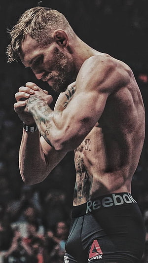 Conor McGregor in a Focused Pre-Fight Prayer with Reebok Shorts and Visible Tattoos HD phone wallpaper