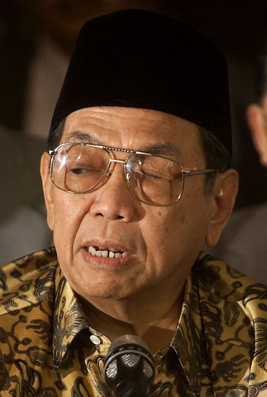 Gus Dur Portrait in Traditional Batik Shirt and Black Cap Speaking at Microphone HD phone wallpaper