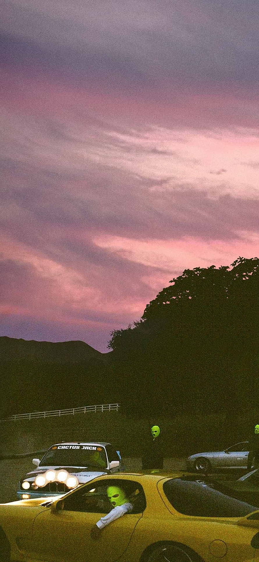 Cactus Jack masked figures in yellow and white cars under a pink sunset sky HD phone wallpaper