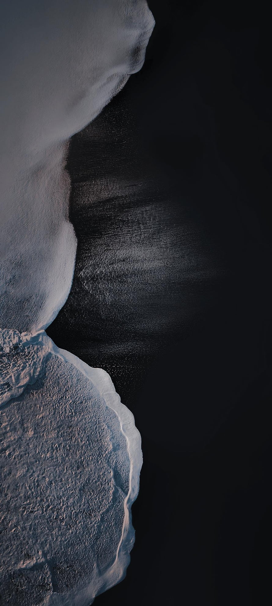 Minimalist Aerial View of Snow-Covered Coastline Against Dark Ocean Water HD phone wallpaper
