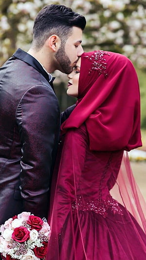 Muslim Wedding Couple in Elegant Burgundy Gown and Dark Suit Sharing a Tender Moment HD phone wallpaper