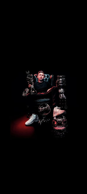 Lionel Messi Seated in a Dark Room Surrounded by Ballon d'Or Trophies and Soccer Balls HD phone wallpaper