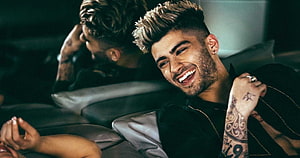 Zayn Malik smiling with tattoos in a dark leather interior HD wallpaper