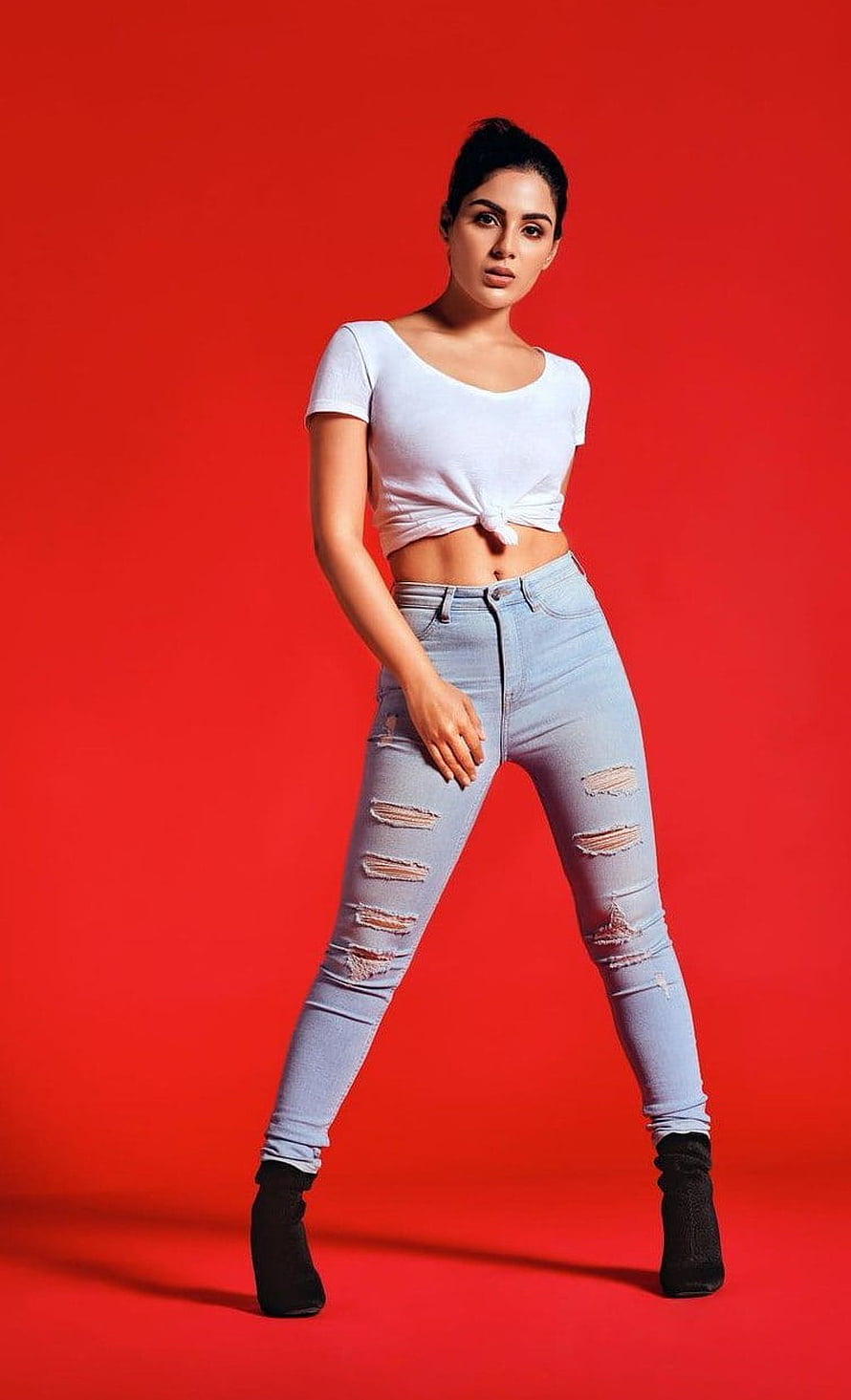 Samyuktha Menon in White Knotted Top and Distressed Denim Jeans on Red Background HD phone wallpaper