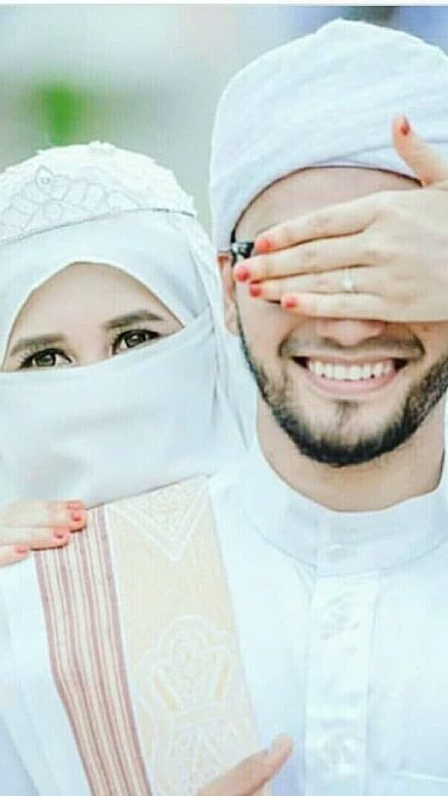 Smiling Muslim Couple in Traditional White Attire with Hijab and Cap HD phone wallpaper