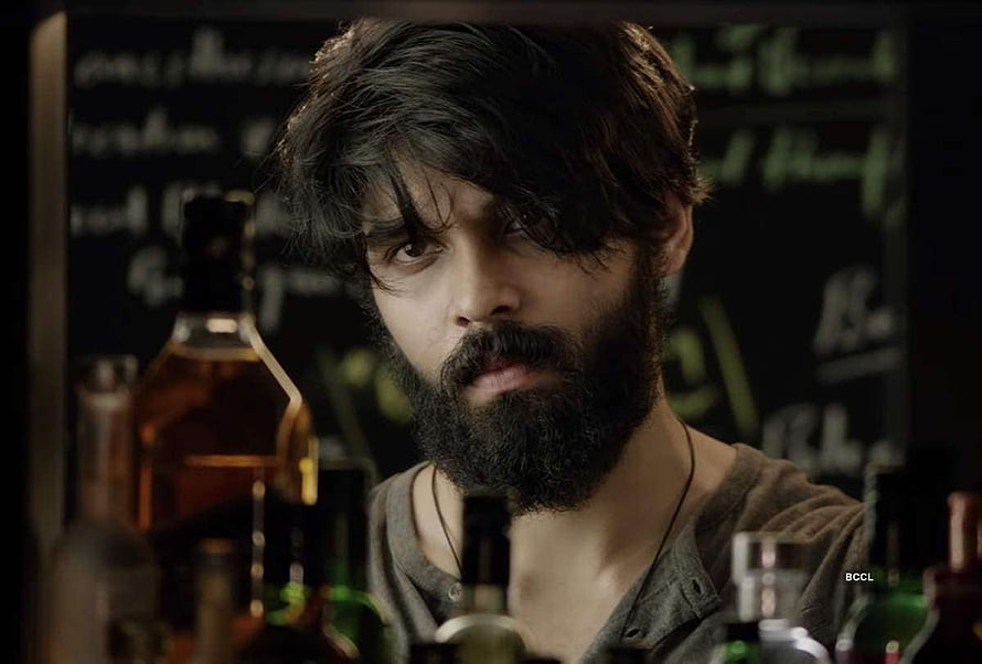 Adithya Varma in a moody bar scene with whiskey bottles and a chalkboard menu HD wallpaper