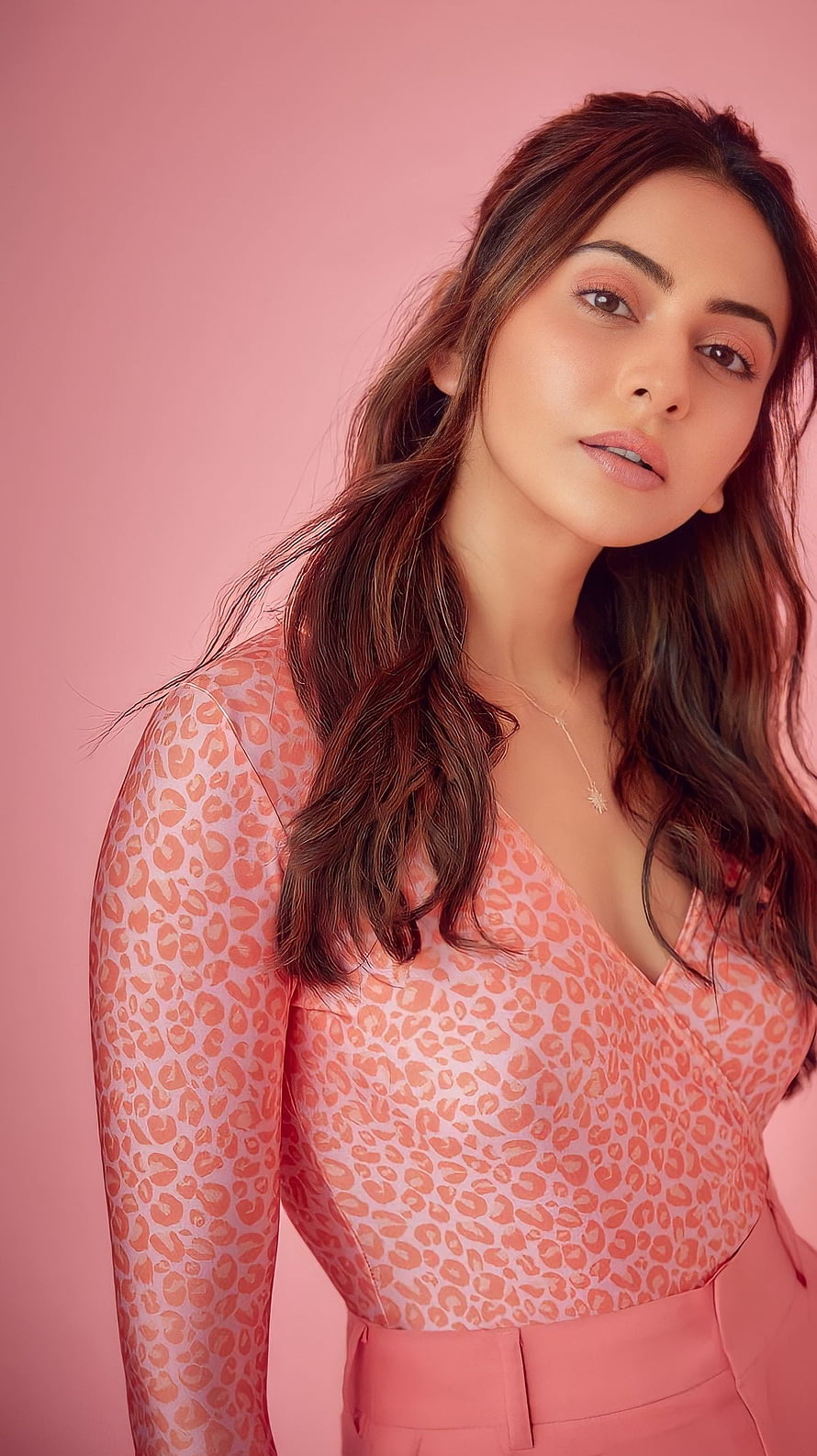 Rakul Preet Singh in a pink leopard print top and matching trousers against a soft pink studio backdrop HD phone wallpaper