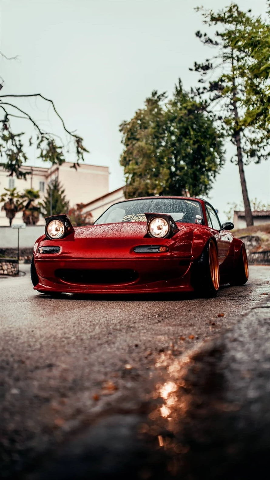 Red Mazda Miata with pop-up headlights parked on a wet street HD phone wallpaper