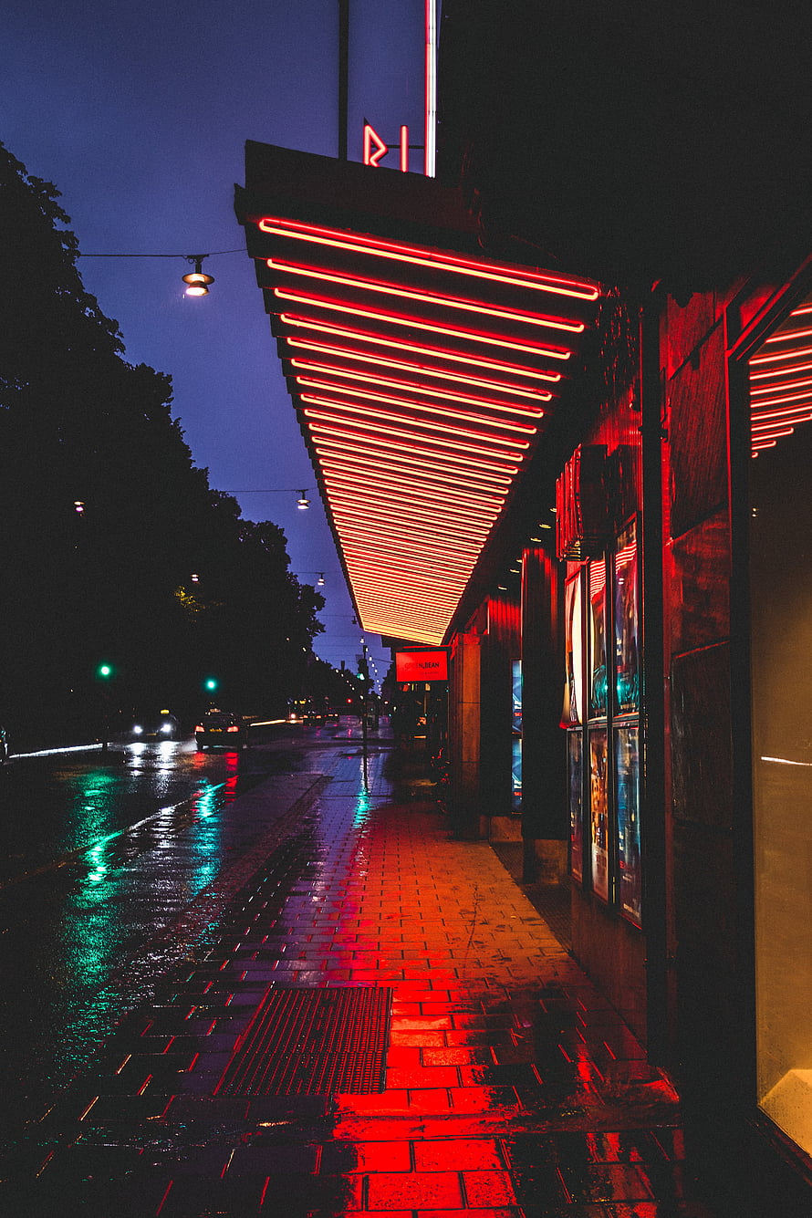 Neon-lit Stockholm street at night with wet pavement reflecting red and green city lights HD phone wallpaper