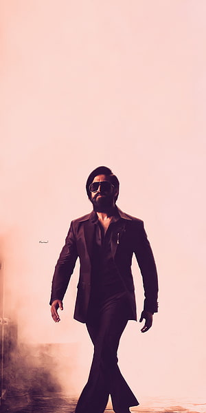 Kamal Haasan in a stylish black suit and sunglasses walking confidently against a pink background HD phone wallpaper