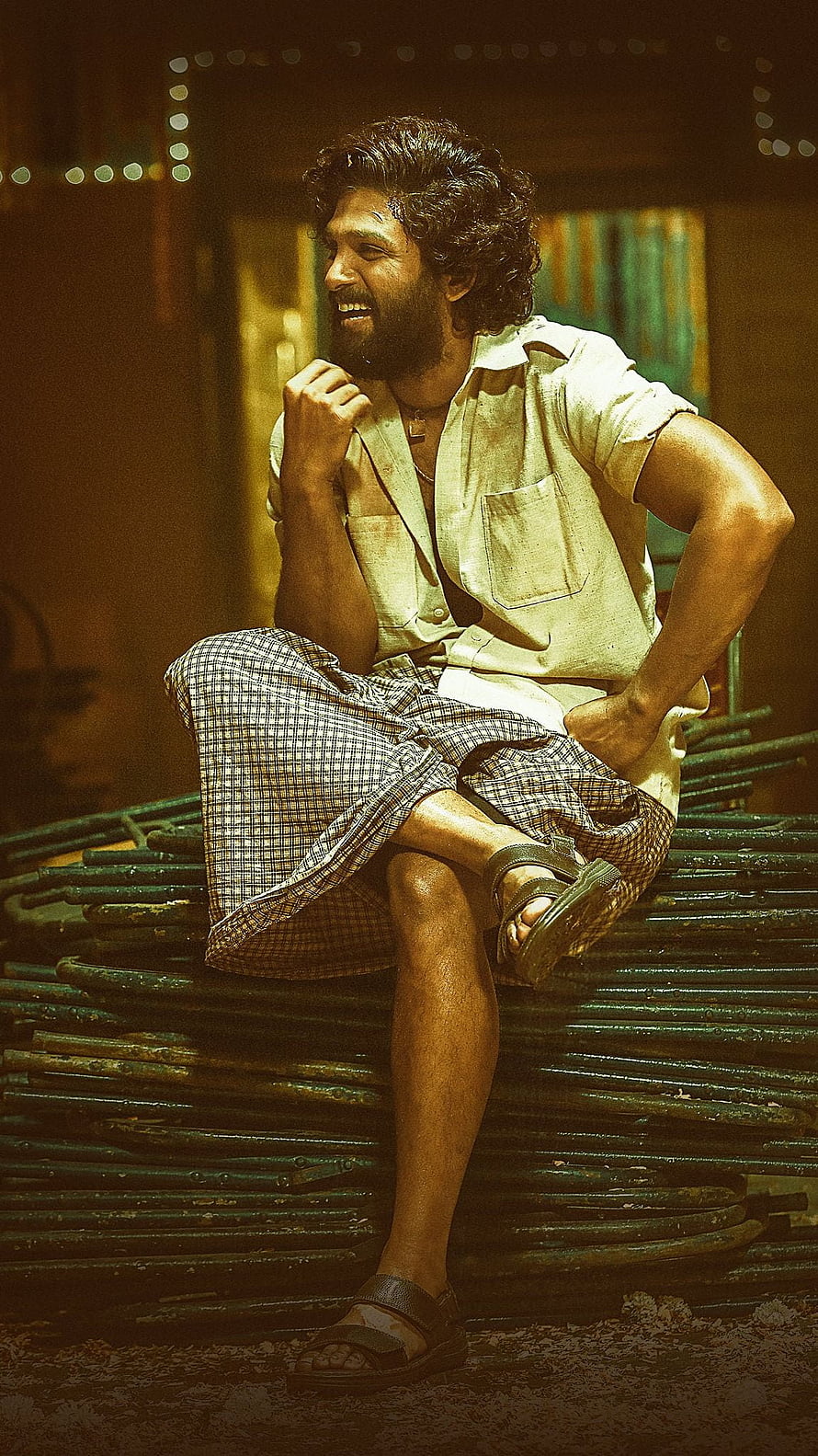 Allu Arjun as Pushpa in a gritty industrial setting wearing a lungi and open shirt HD phone wallpaper