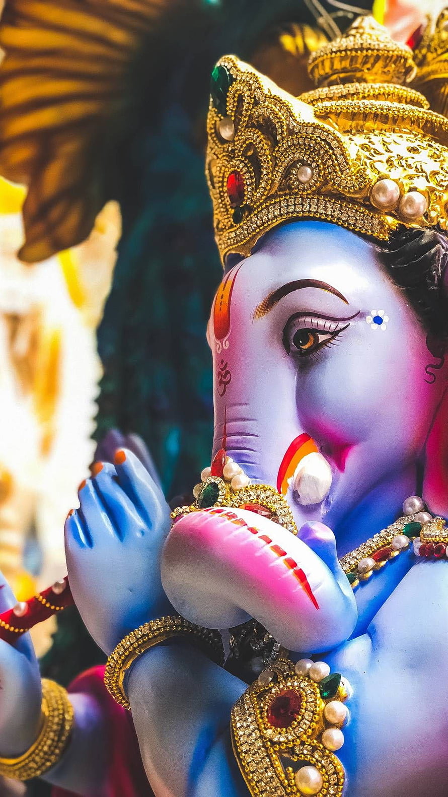 Close-up of Lord Ganesha Statue with Blue Skin, Golden Crown, and Intricate Jewelry HD phone wallpaper