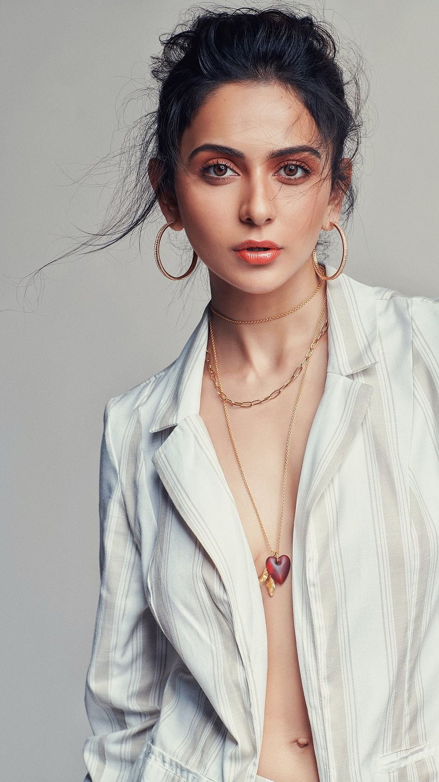 Portrait of a woman with dark hair in an updo wearing a white striped blazer, gold hoop earrings, and a heart pendant necklace, Rakul Preet singh, telugu actress, model HD phone wallpaper