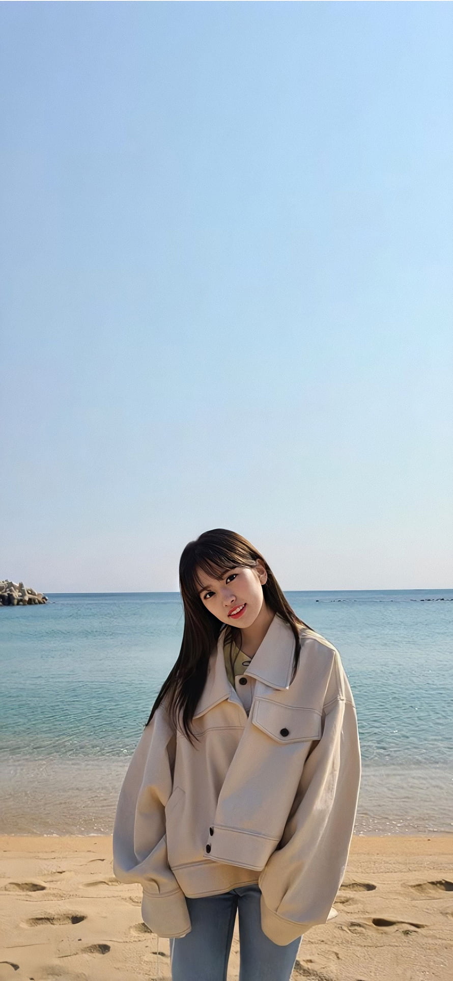 Ahn Yujin in a cream jacket on a sunny beach with turquoise water and clear blue sky HD phone wallpaper