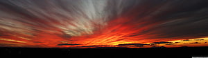 Vivid Crimson Sunset Sky with Dramatic Streaked Clouds Over Dark Horizon HD wallpaper