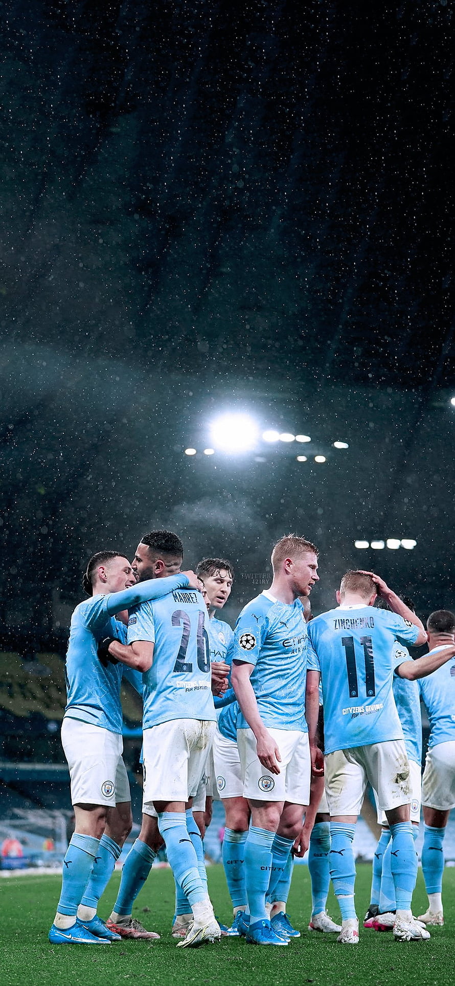 Manchester City Players Gathered On The Pitch Under Stadium Floodlights During A Rainy Night Match HD phone wallpaper