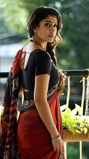 Sai Pallavi in a stunning red and black saree with traditional jewelry posing outdoors HD phone wallpaper