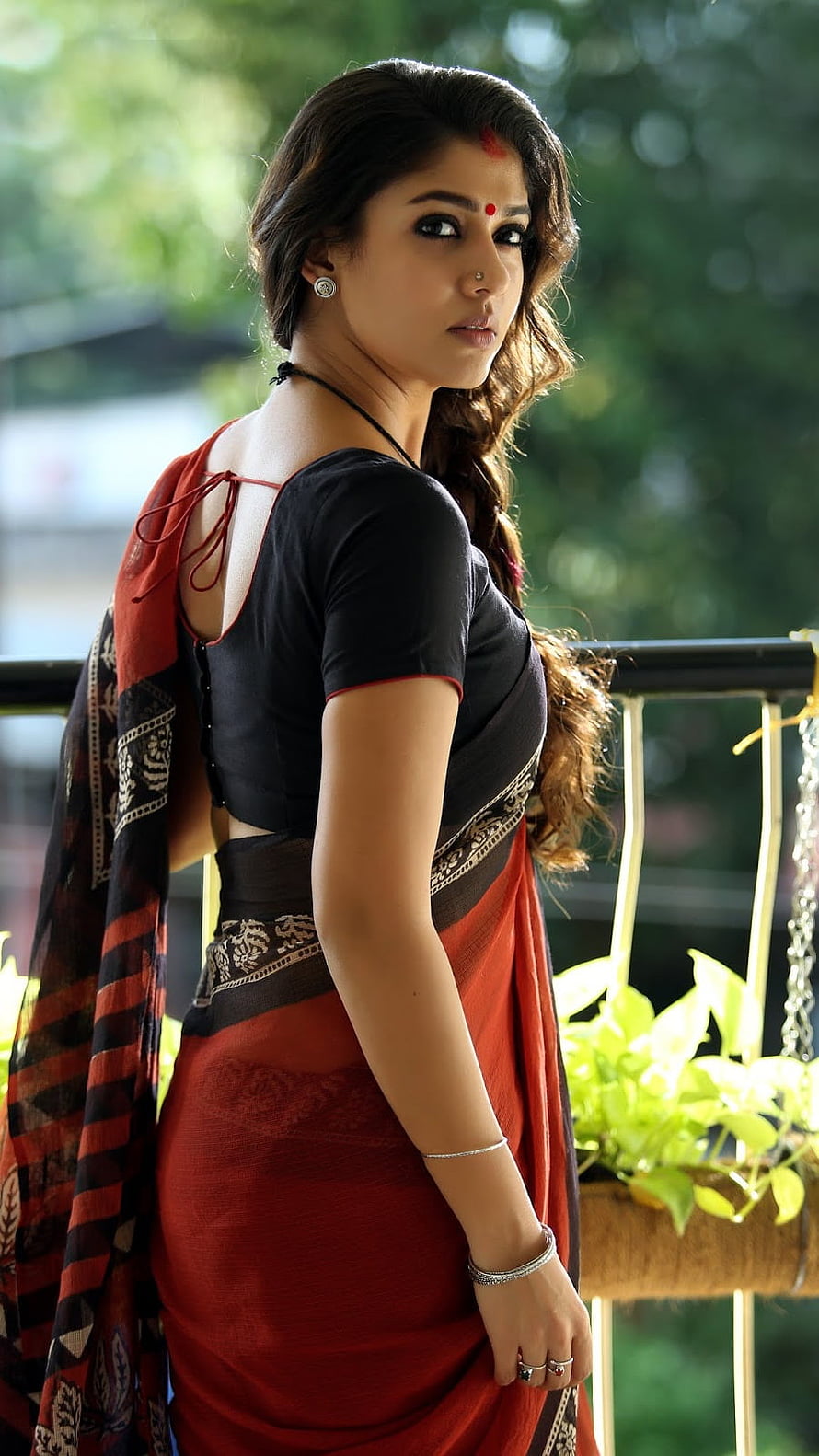 Sai Pallavi in a stunning red and black saree with traditional jewelry posing outdoors HD phone wallpaper