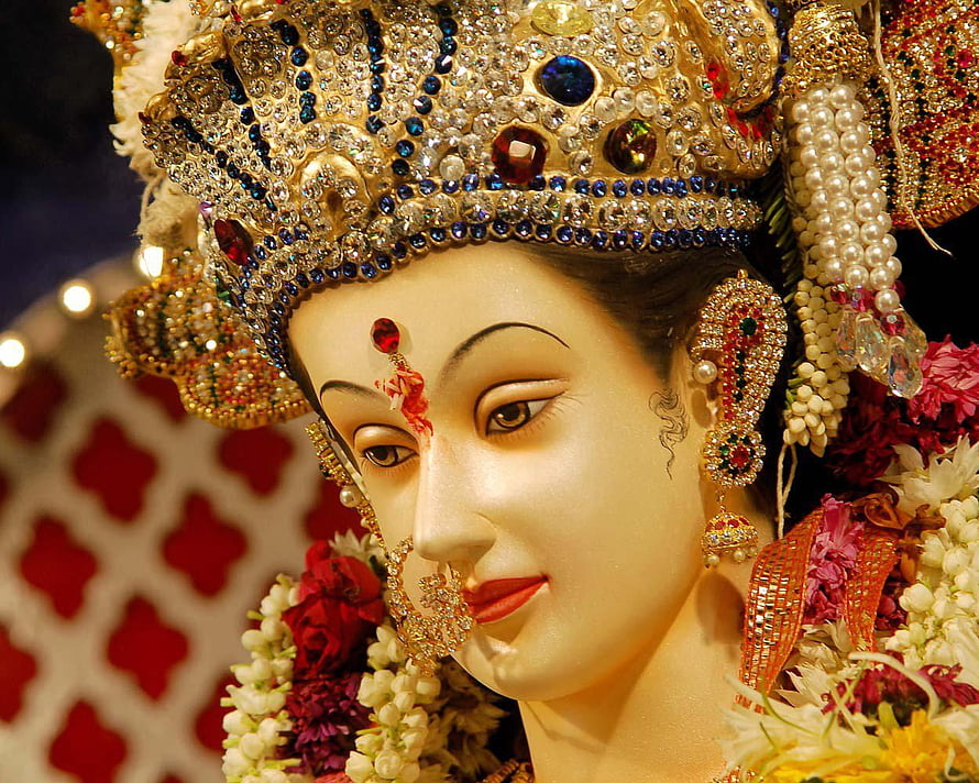 Close-up of a beautifully adorned Hindu goddess idol with intricate jewelry and floral garlands HD wallpaper