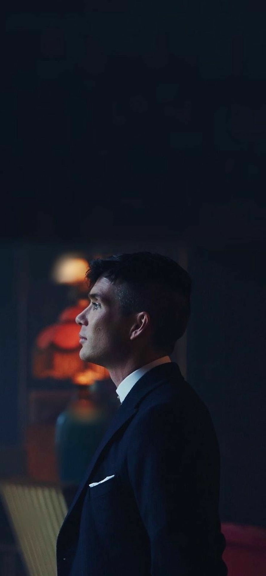 Tommy Shelby from Peaky Blinders in a dark suit looking up in a dimly lit room HD phone wallpaper