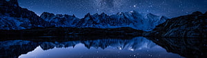 Snow-Capped Mountain Range Reflected in a Calm Alpine Lake Under a Starry Night Sky HD wallpaper
