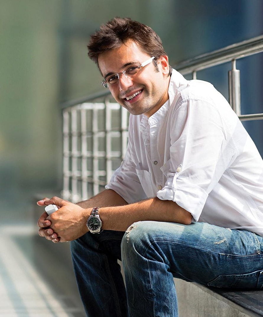 Sandeep Maheshwari smiling in white shirt and glasses sitting on a ledge HD phone wallpaper