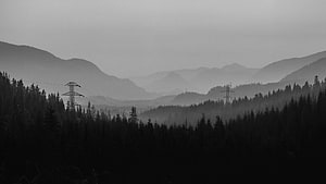 Monochrome Misty Mountain Valley With Silhouetted Forest And Power Lines HD wallpaper