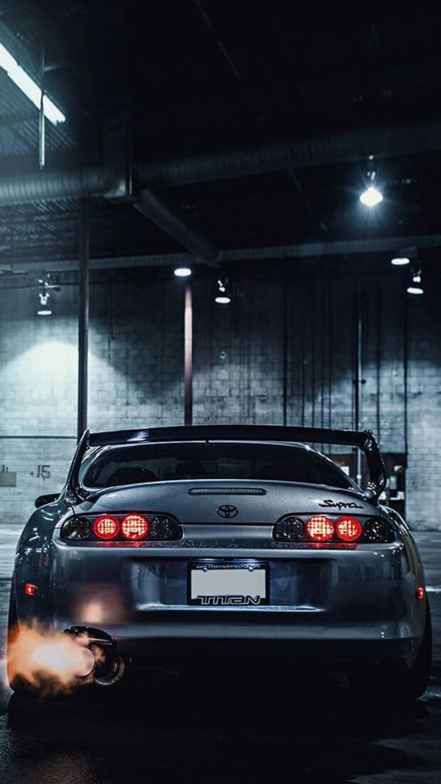 Silver Toyota Supra with Flames Shooting from Exhaust in Dark Garage HD phone wallpaper